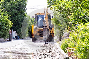 Excavator breaking and drilling the concrete road for repairing. Large pneumatic hammer mounted on the hydraulic arm of a construc