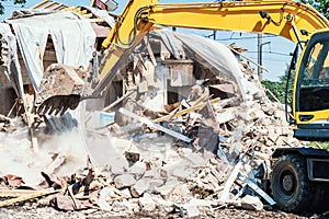 Excavator breaks old house. Process of demolition building. Construction industry and development concept