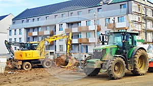 Excavator with a bucket at the construction site, building a block of flats