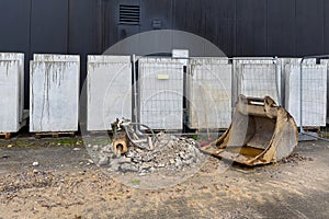 Excavator bucket on a construction site next to a pile of construction waste.