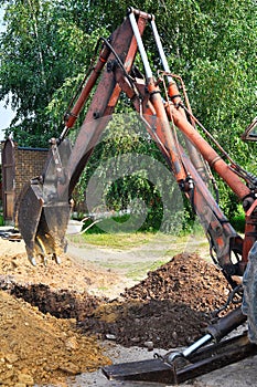 Excavator bucket digging a trench in the dirt ground