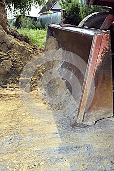 Excavator bucket digging a trench in the dirt ground