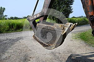 Excavator bucket digging a trench in the dirt ground