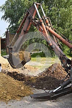 Excavator bucket digging a trench in the dirt ground