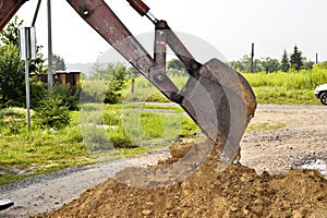 Excavator bucket digging a trench in the dirt ground