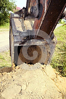 Excavator bucket digging a trench in the dirt ground