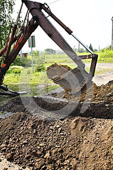 Excavator bucket digging a trench in the dirt ground