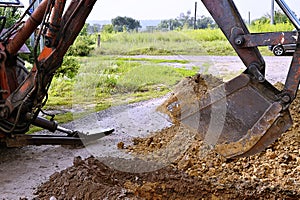 Excavator bucket digging a trench in the dirt ground