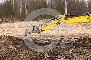 Excavator bucket digging a trench in the ground at a construction site. Excavation industrial work with land and soil