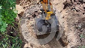 Excavator bucket when excavating soil. Work of construction equipment on construction site