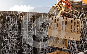 Excavator bucket in front of the ruin of a partially demolished high-bay warehouse photo