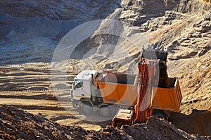 Excavator bucket loading sand into the body of a heavy dump truck