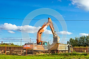 Excavator bucket loads heavy truck with ground