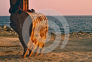 Excavator bucket by the seaside at sunset