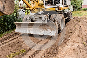 Excavator or bulldozer bucket flattens the ground or road in the industrial zone or construction site