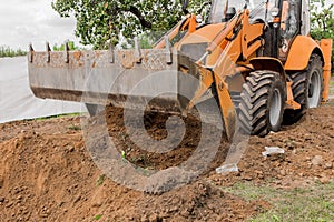 Excavator or bulldozer bucket flattens the ground or road in the industrial zone or construction site