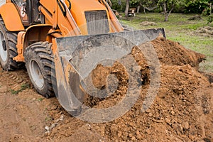 Excavator or bulldozer bucket flattens the ground or road in the industrial zone or construction site