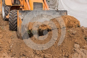 Excavator or bulldozer bucket flattens the ground or road in the industrial zone or construction site