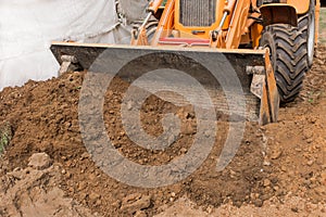 Excavator or bulldozer bucket flattens the ground or road in the industrial zone or construction site