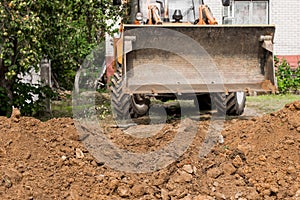 Excavator or bulldozer bucket flattens the ground or road in the industrial zone or construction site