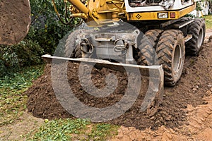 Excavator or bulldozer bucket flattens the ground or road in the industrial zone or construction site