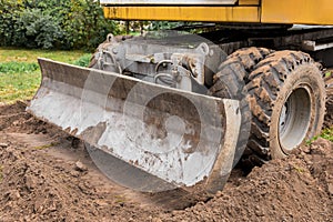 Excavator or bulldozer bucket flattens the ground or road in the industrial zone or construction site