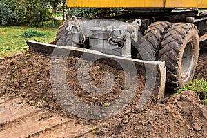 Excavator or bulldozer bucket flattens the ground or road in the industrial zone or construction site