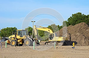 Excavator and bulldozer at a construction site with a large pile of dirt