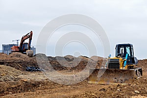 Excavator and a bulldozer work at a construction site. Land clearing, grading, pool excavation, utility trenching and foundation