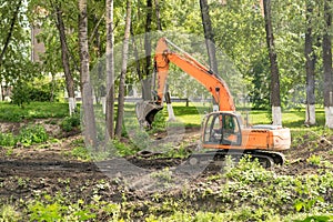 Excavator in the city among the trees.