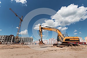 Excavator at a construction site against the background of a tower crane. Construction, technology