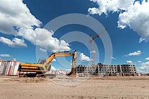 Excavator at a construction site against the background of a tower crane. Construction, technology