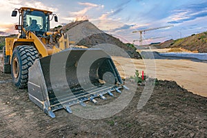 Excavator in a construction site with a crane in the background