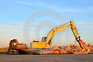 Excavator on a construction site cuts and crumbles old concrete and asphalt.