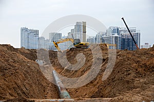 Excavator at construction site during laying sewer and main reticulation systems. Civil infrastructure pipe, water lines, sanitary photo