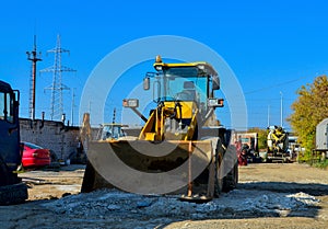 Excavator on the construction site is preparing to load the soil into the dump truck. Wheel loader with iron bucket