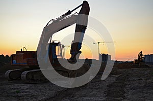 Excavator at construction site on sunset background. Earth-moving heavy equipment for digg ground, foundation and trenchs for