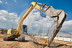 Excavator crasher machine crushing pole wit jaws on construction site