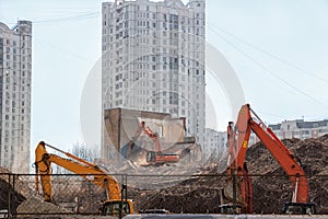 Excavator demolition dismantles the building on background of li