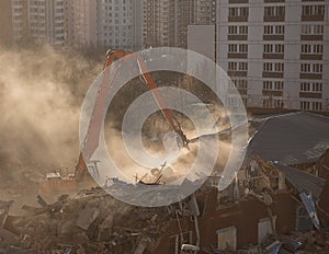 Excavator demolition in sunlit dust cloud dismantles the building in residential area