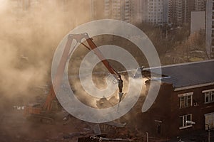 Excavator demolition in sunlit dust cloud dismantles the building in residential area