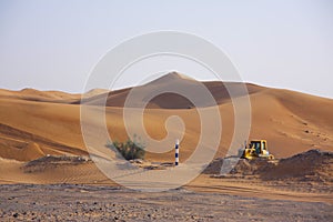 Excavator among desert sand dunes