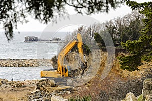 Excavator destroying a beach and a cliff for a hotel construction.