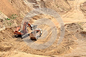 Excavator developing the sand on the opencast and loading it to the heavy dump truck