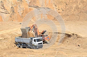 Excavator developing the sand on the opencast and loading it to the heavy dump truck. Processing of loose material in mining