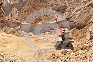 Excavator developing the sand on the opencast and loading it to the heavy dump truck. Processing of loose material in mining