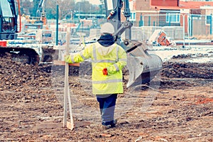 Excavator digging and levelling ground on construction site. Digging to the correct level with help of profiles and traveller