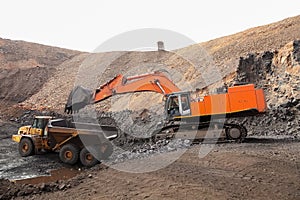 Excavator digging and loading ore rocks on a Manganese mine