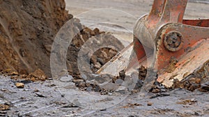 The excavator is digging the soil in close-up. Excavator bucket rakes clay soil. Open pit mining. Slow motion, 4k, 60fps