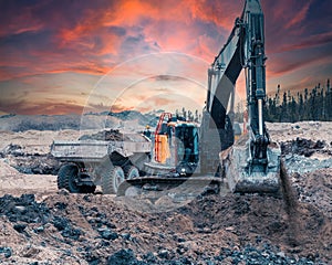 Excavator digging soil on a site at sunset